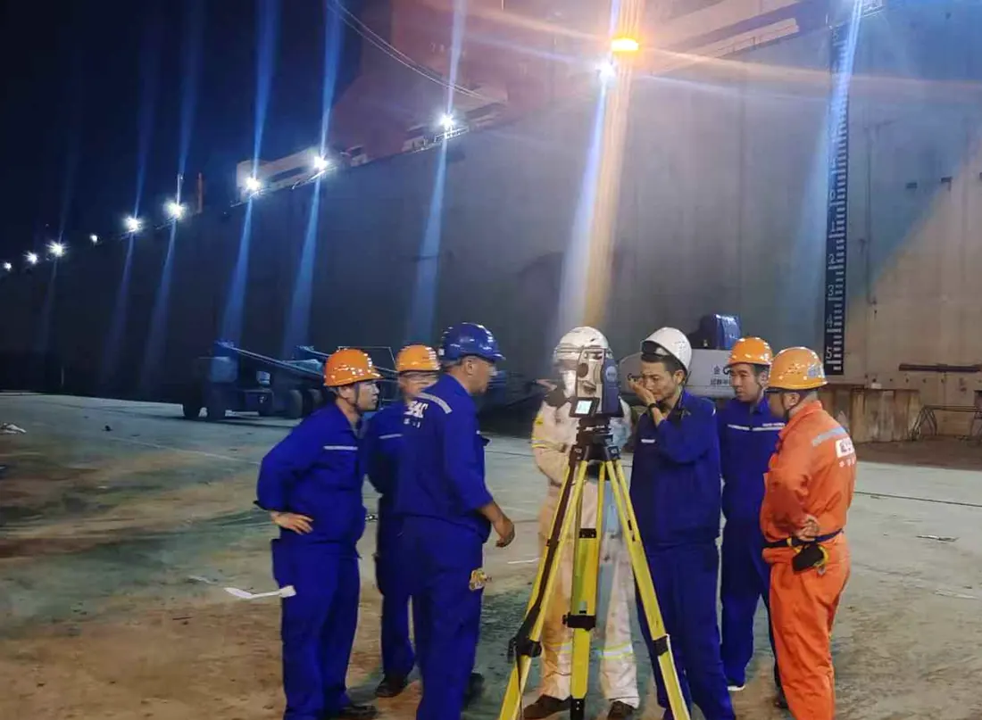 Technical team carrying out precision survey work in a shipyard